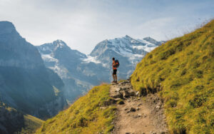 A traveller/hiker enjoys the beautiful view of Oeschinensee, the blue lake with the snow alpine as the background